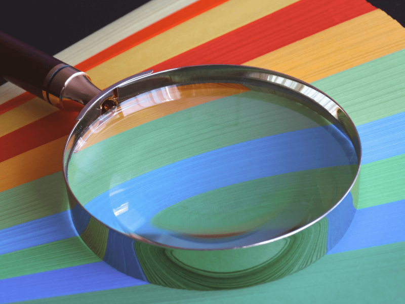 eine Lupe liegt auf gefächerten bunten Karteikarten