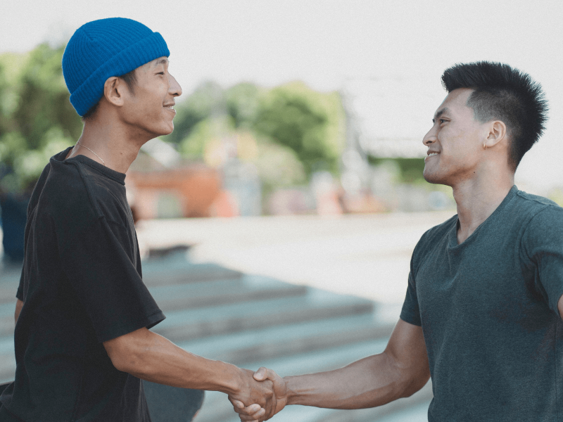 zwei Jugendliche geben sich lächelnd die Hand