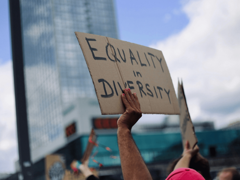 ein Schild wird hochgehoben auf dem "Equality in Diversity" steht
