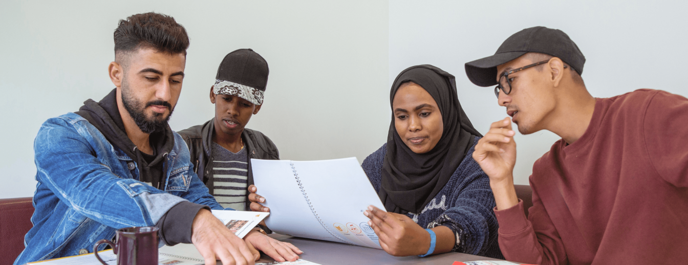DaZ-Lernende sitzen zusammen an einem Tisch im Klassenraum und arbeiten an einer Mathematik in DaZ Aufgabe