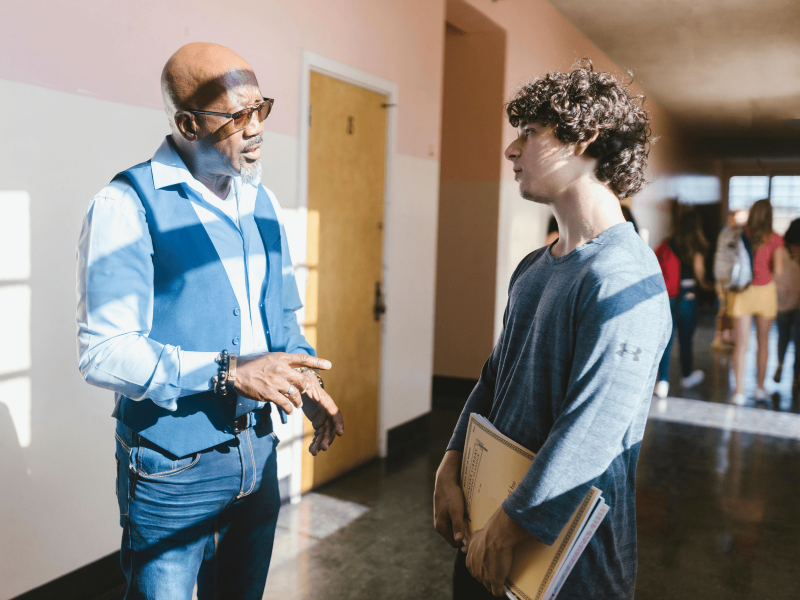 eine Schwarze Lehrkraft redet mit einem Schüler über Traumata