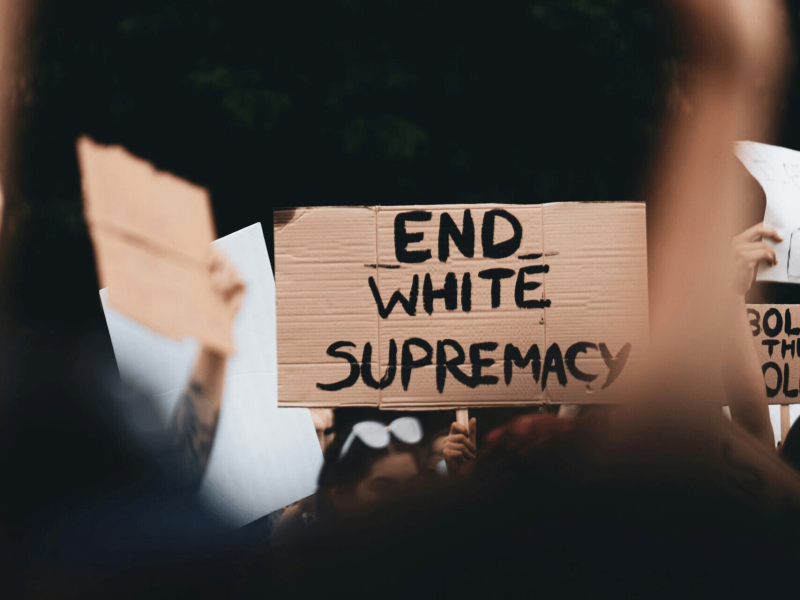 ein Schild wird hochgehoben auf dem "End White Supremacy" steht