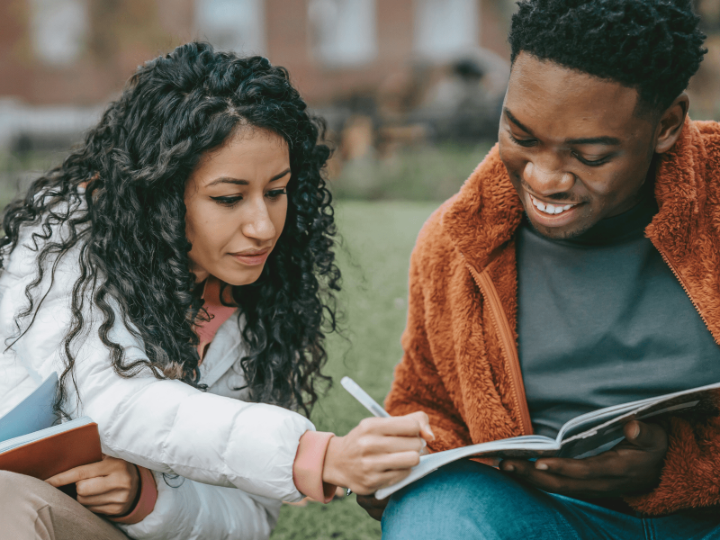 eine Schülerin schreibt Vokabeln in das Heft eines Mitschülers