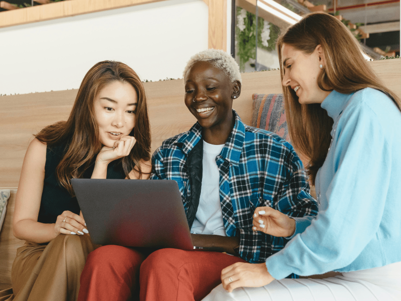 drei Frauen sitzen vor einem Laptop bei einem online workshop